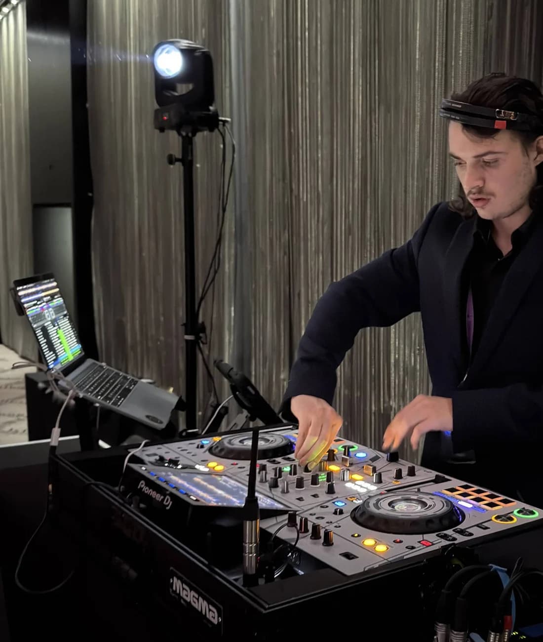 DJ Shakin behind the decks in a tailored jacket at an Adelaide event